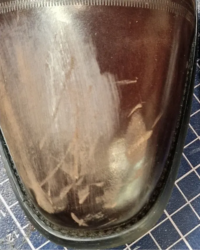 Brown leather shoe with deep scuffs on the toe