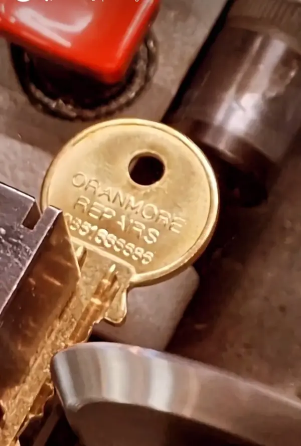 Brass key engraved with the Oranmore Repairs name, in the key machine