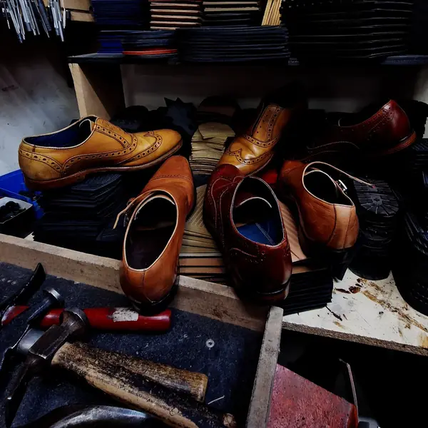 Leather brogues waiting on the workbench beside the cobbler’s hammer