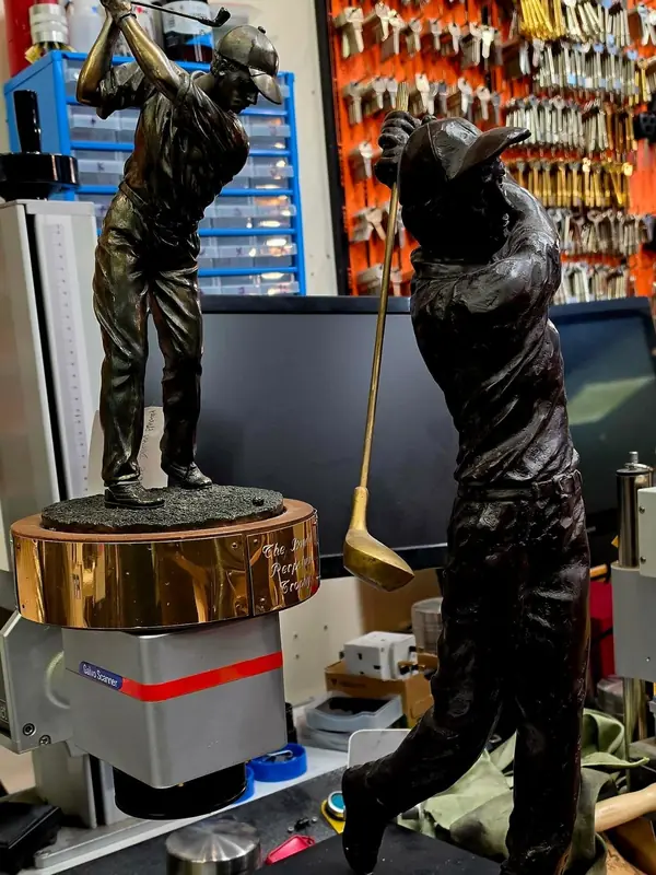 Bronze golfer trophies in front of the key wall